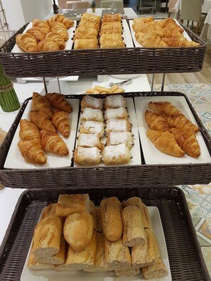 Un bufé con diversos productos de panadería, como cruasanes, pasteles y pan.