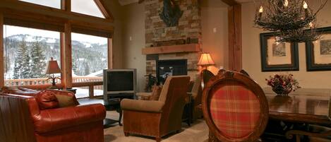 A cozy living room with a fireplace, a television, and a dining area with a chandelier.