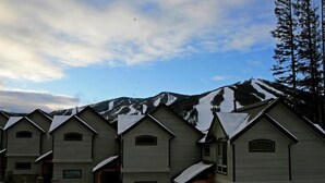 Une rangée de bâtiments de style chalet, avec une montagne enneigée en arrière-plan.