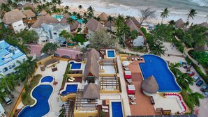 A resort with multiple swimming pools, a beach, and thatched-roof structures.