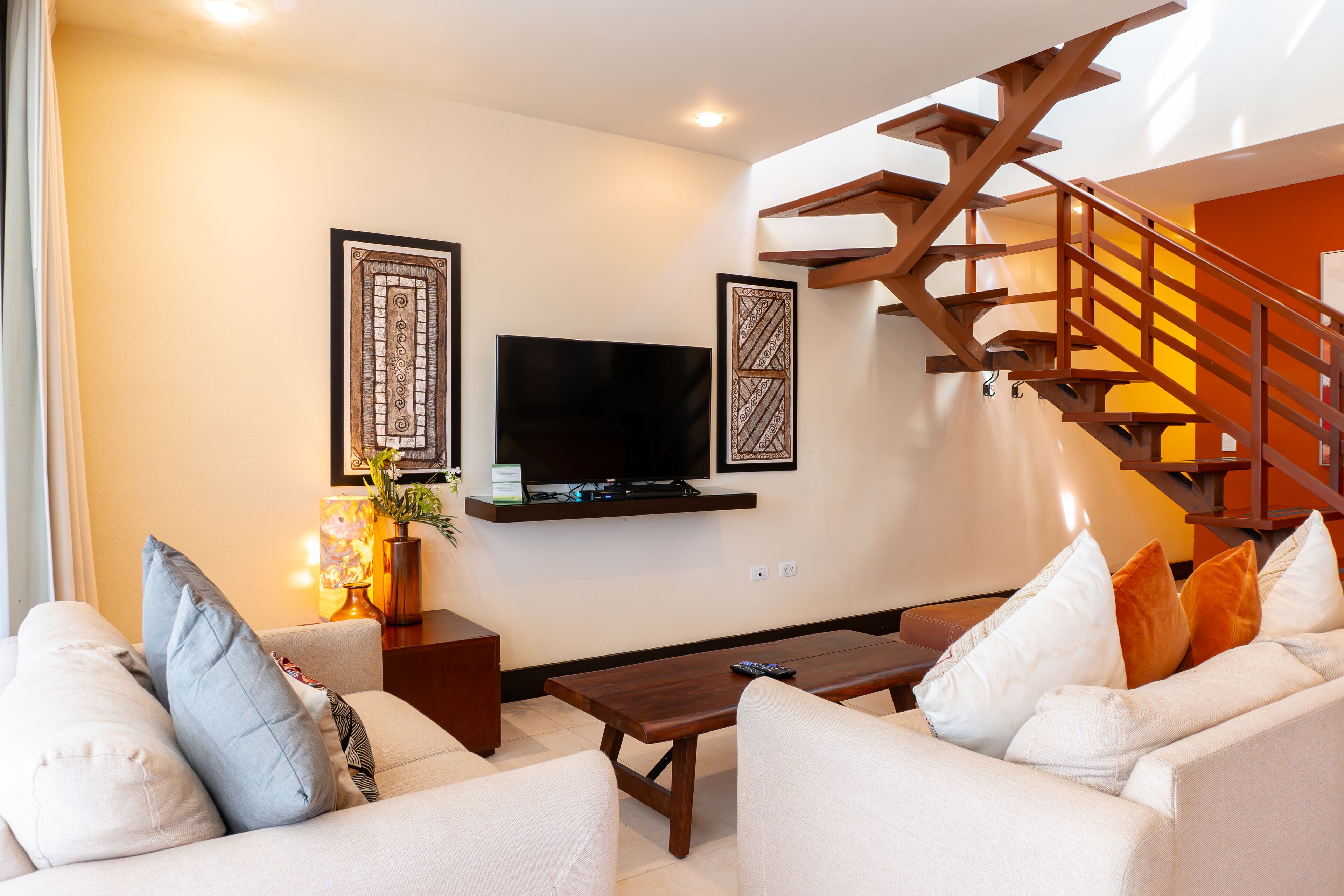 A living room with a sofa, coffee table, and a TV mounted on the wall.