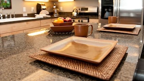 Eine moderne Küche mit Granit Arbeitsplatten, einem Edelstahl-Kühlschrank und einer Mikrowelle.