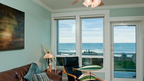 Ein Wohnzimmer mit Blick auf den Ozean, einem Deckenventilator, einem braunen Ledersofa und einem Sessel mit Meerblick.