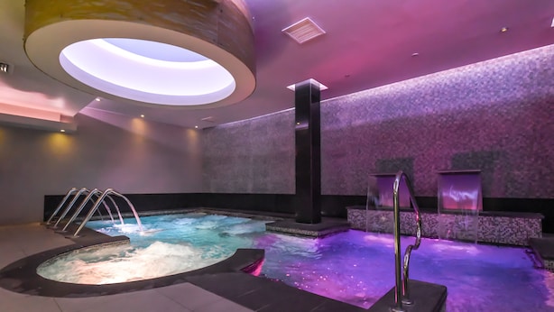 A spa area with a hot tub, a standing shower, and a ceiling light fixture. - Hotel Gran Palace (Santiago)