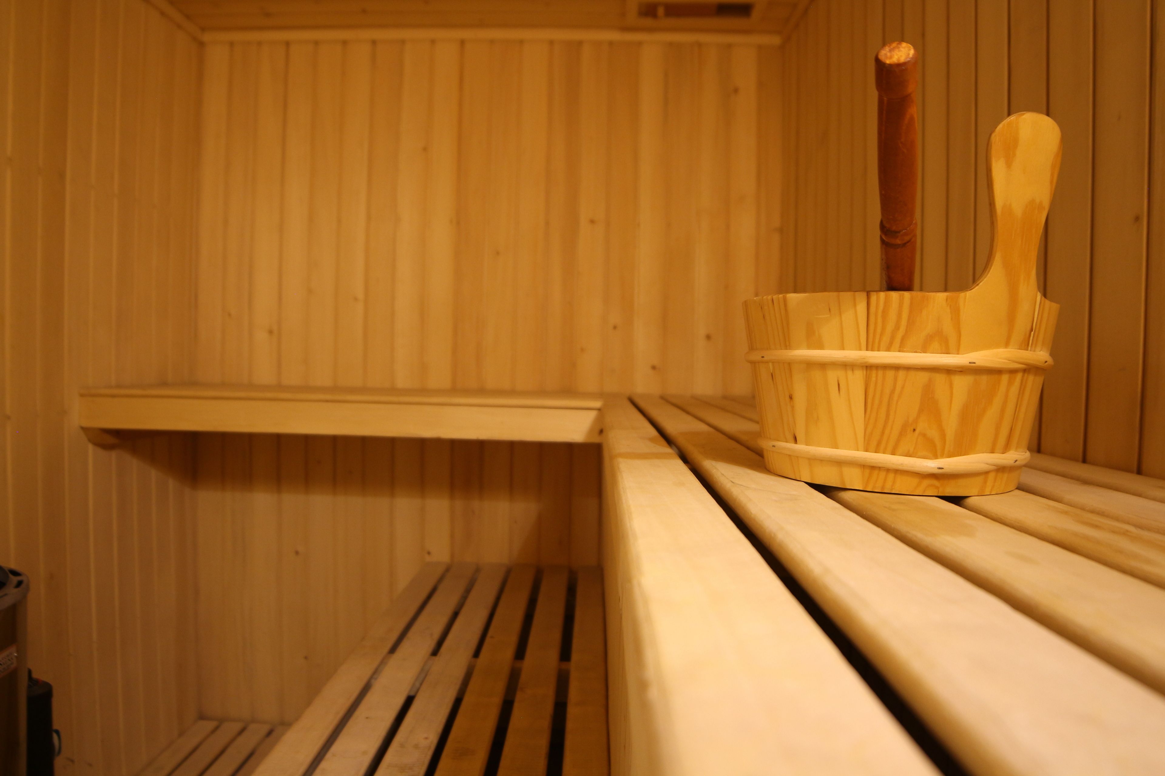 Un sauna en bois avec des bancs et un seau en bois.