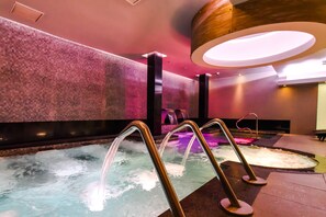 A spa area with a hot tub, water jets, and a textured wall. - Hotel Gran Palace (Santiago)