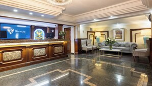 A hotel lobby with a reception desk, seating area, and a chandelier. - Hotel Gran Palace (Santiago)