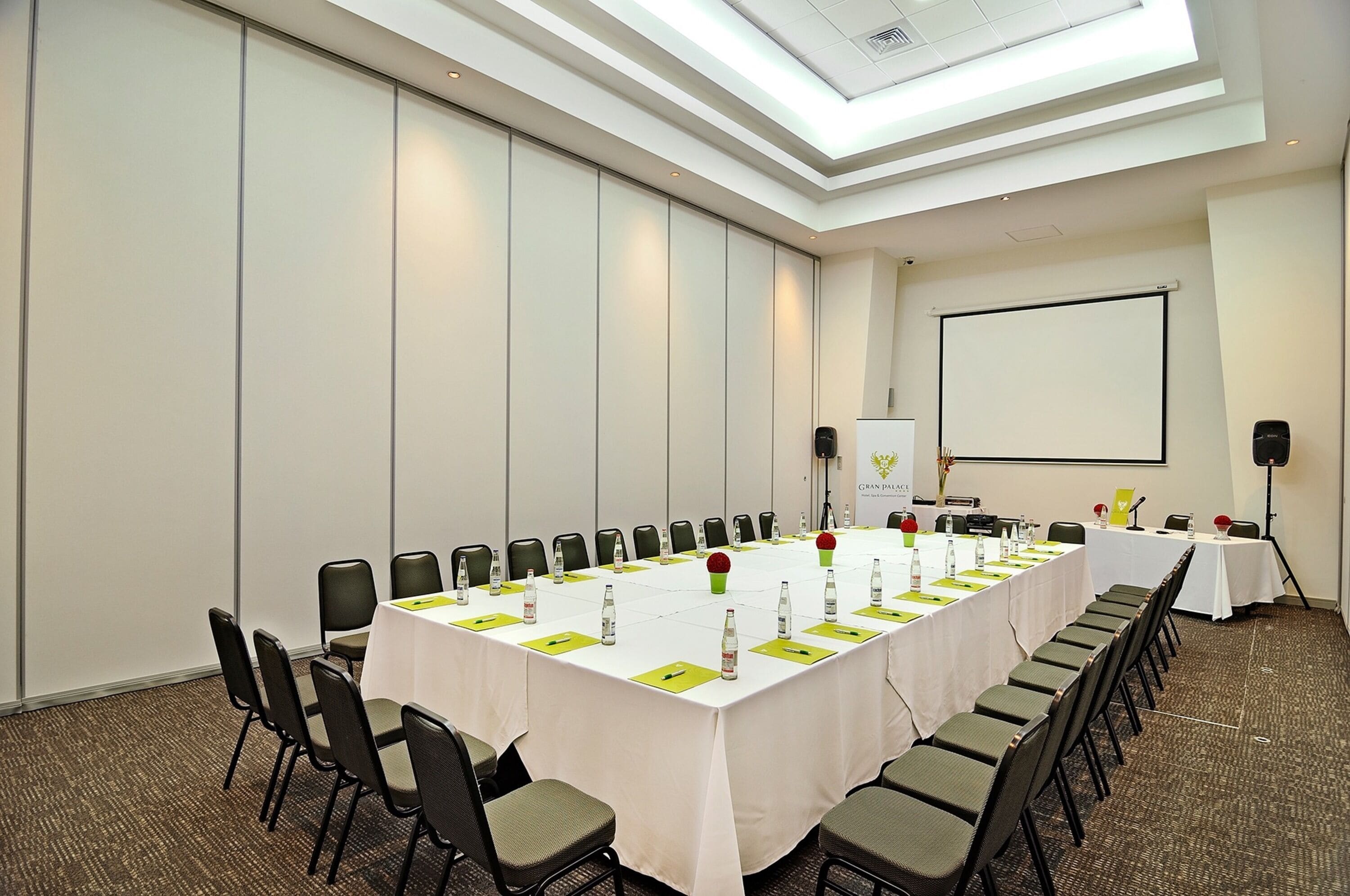 A conference room with a long table, chairs, a projector screen, and a whiteboard.