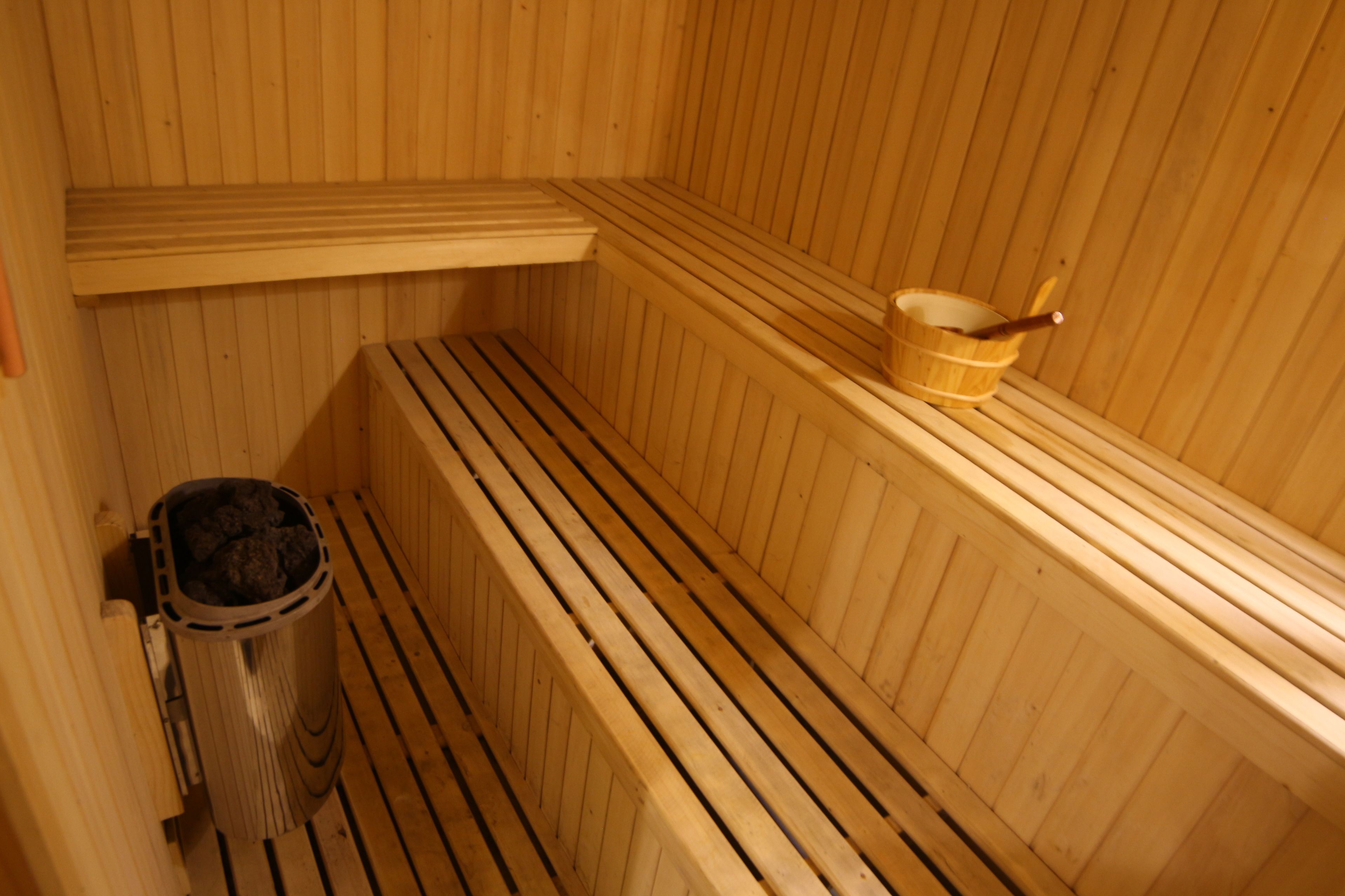 Un sauna avec des bancs en bois et un seau en bois.