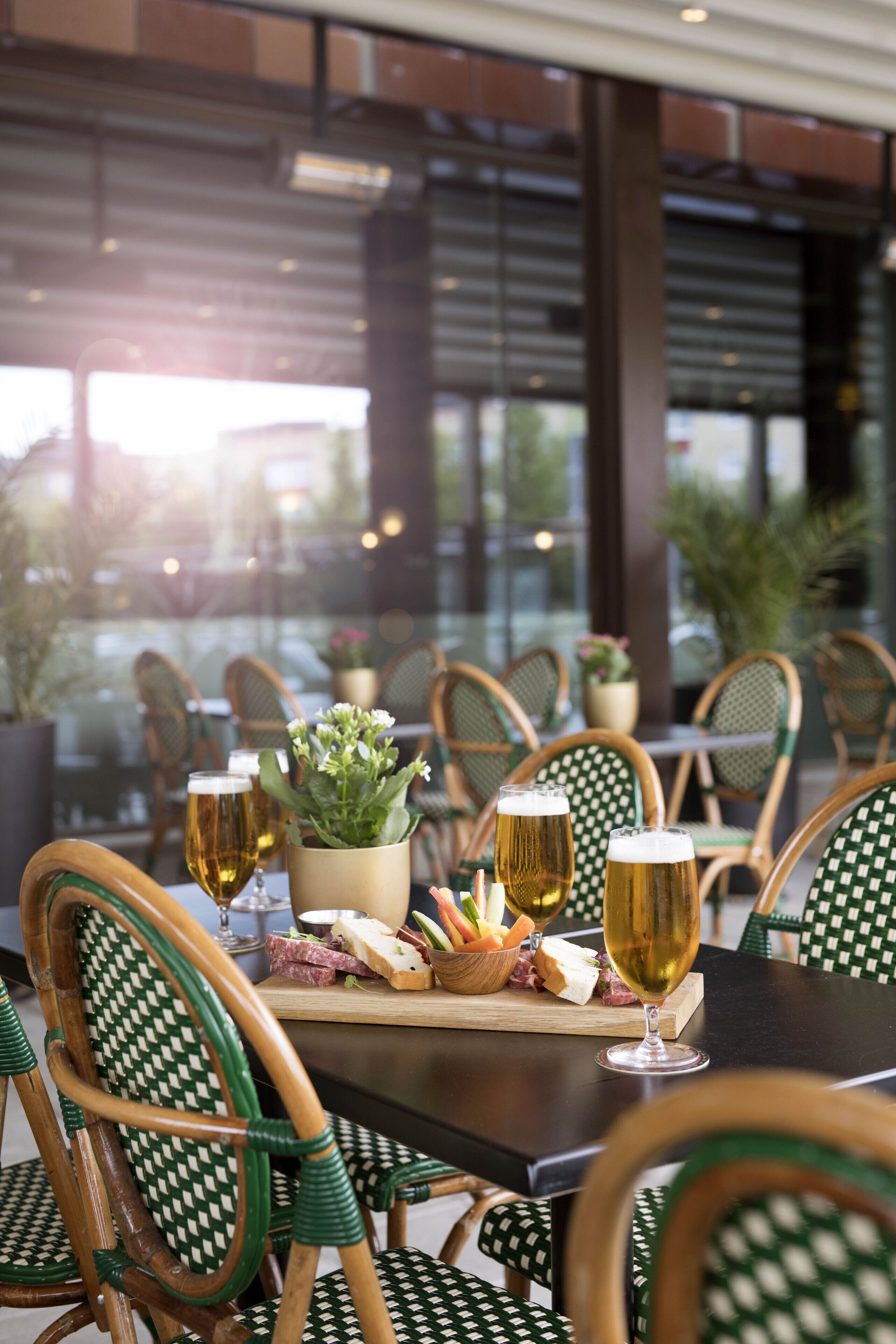Un ambiente de restaurante con una mesa lista para comer, que incluye sillas, una planta pequeña y diversos alimentos.