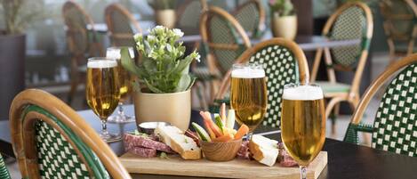 Un ambiente de restaurante con una mesa lista para comer, que incluye sillas, una planta pequeña y diversos alimentos.
