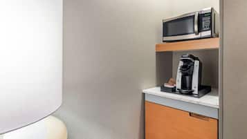 Un baño pequeño con inodoro, microondas y cafetera sobre una encimera.