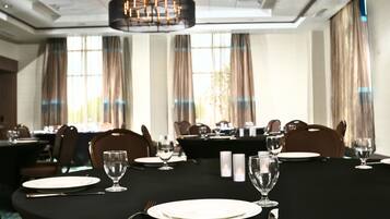 A dining area with tables set for a meal, featuring chairs, plates, cutlery, and glasses.