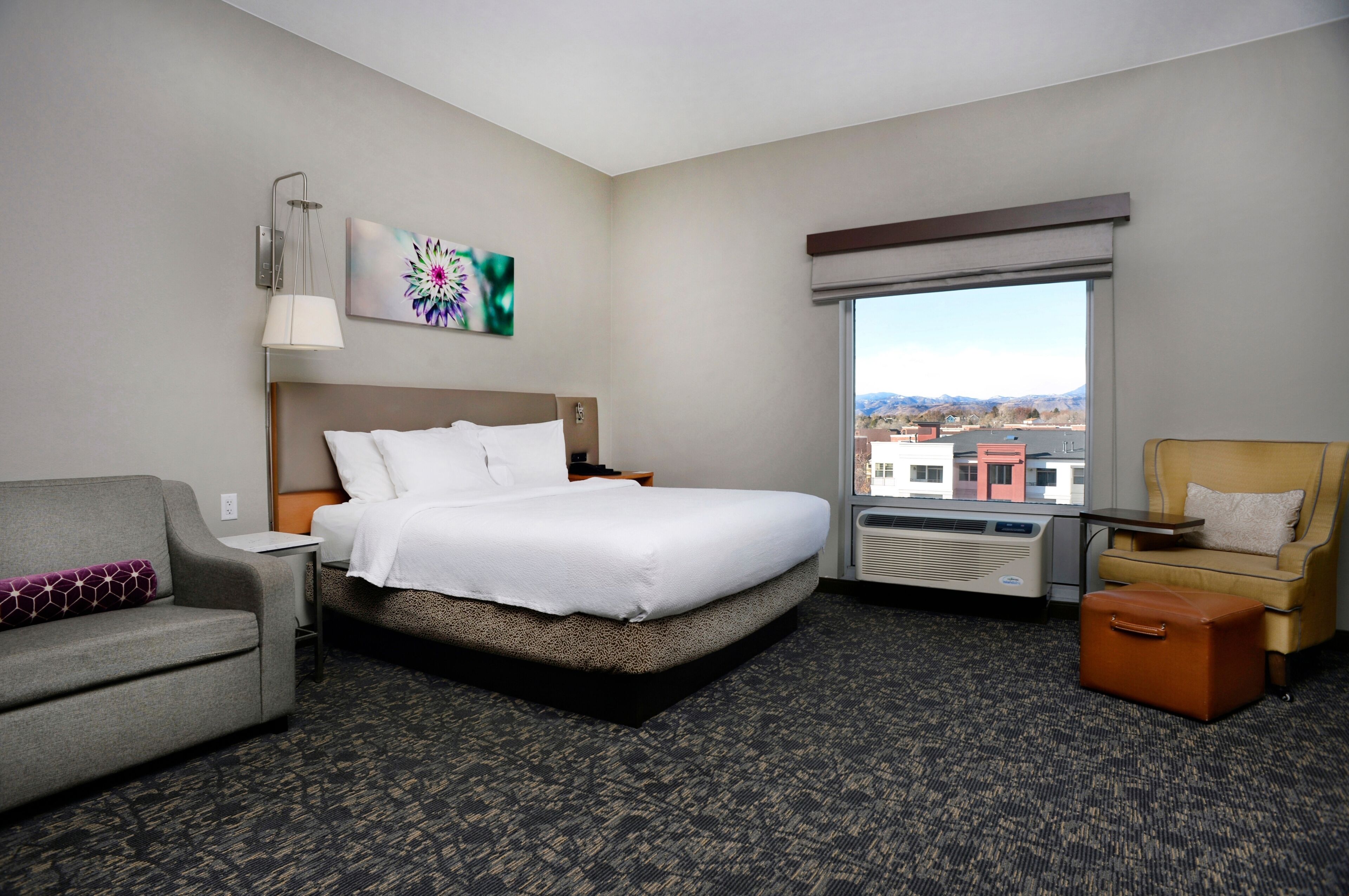 A hotel room with a bed, a sofa, a chair, a table, and a window with a view.