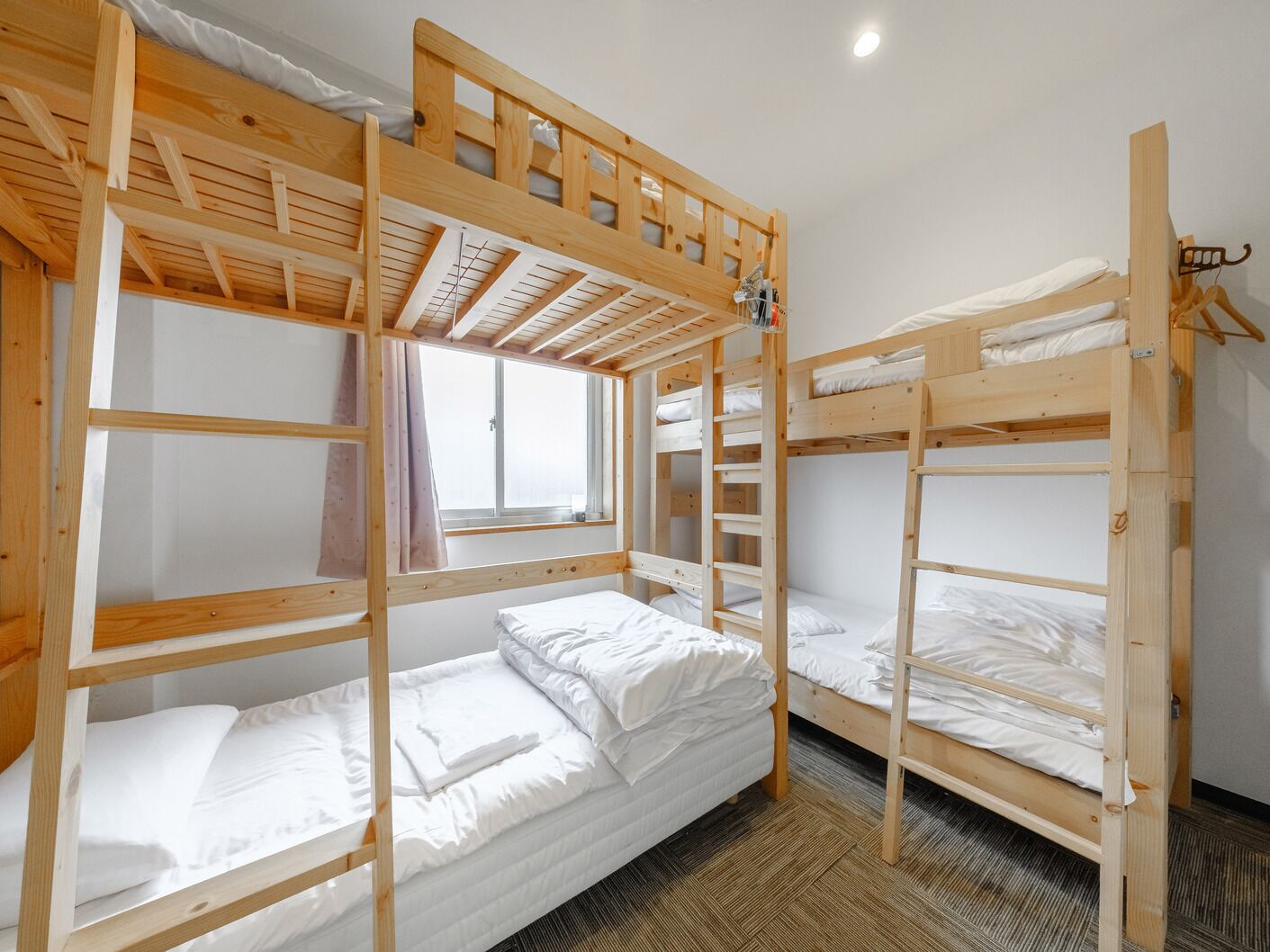 Quarto com beliche, janela e teto de madeira.