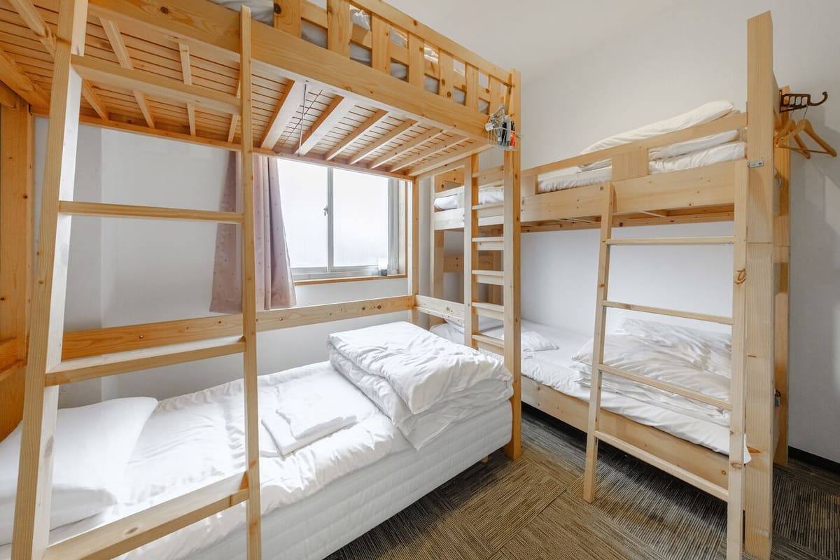 A bunk bed room with a window and a wooden ceiling.