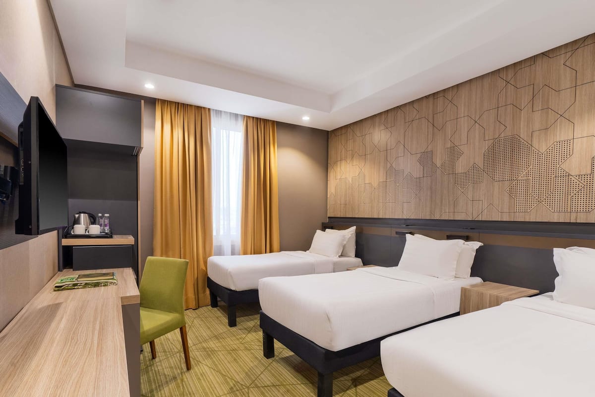 Een hotelkamer met twee bedden, een bureau, een stoel en een televisie.