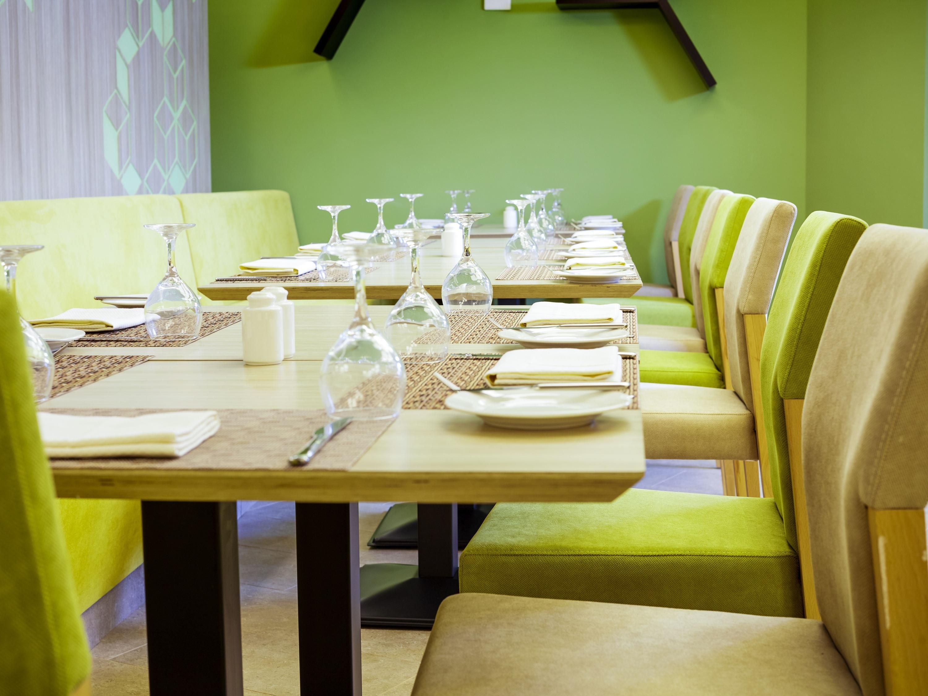 Un restaurante con una larga mesa dispuesta para una comida, incluyendo platos, vasos y cubiertos.