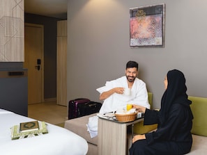 A hotel room with a bed, a sitting area with a table, and a wall-mounted artwork. - ibis Styles Makkah (Makkah)