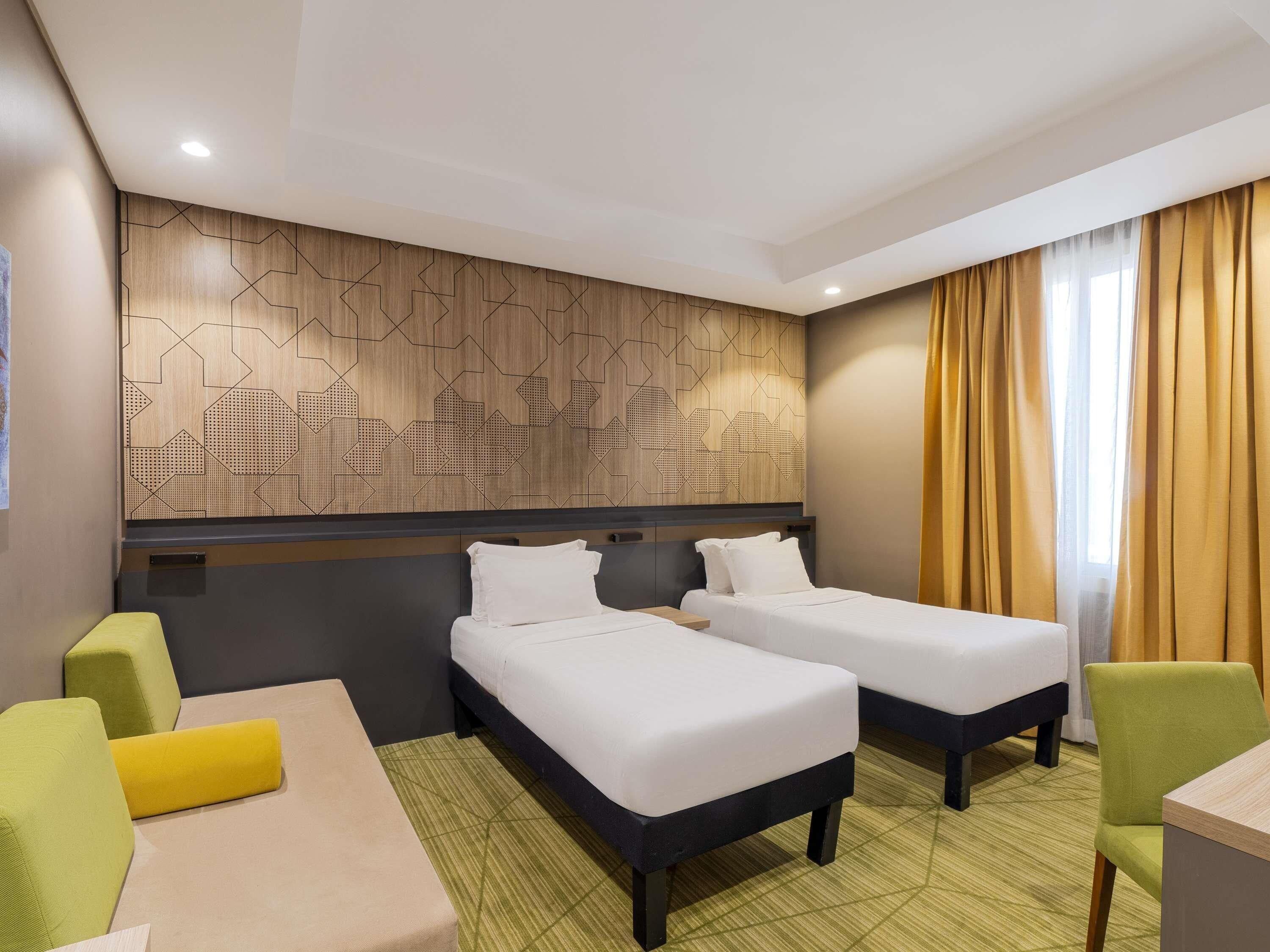 Une chambre d’hôtel avec deux lits, un bureau et une chaise.