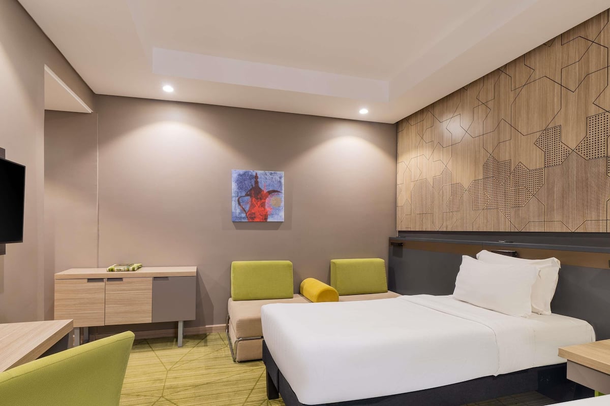 Quarto de hotel moderno com uma cama, uma escrivaninha e duas cadeiras.