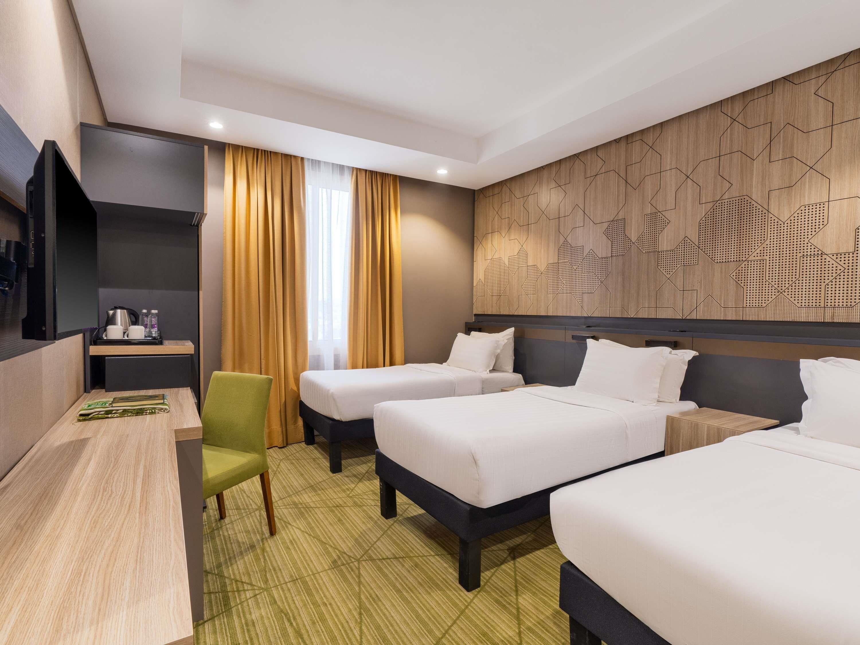 Une chambre d’hôtel avec deux lits, un bureau, une chaise et un téléviseur.