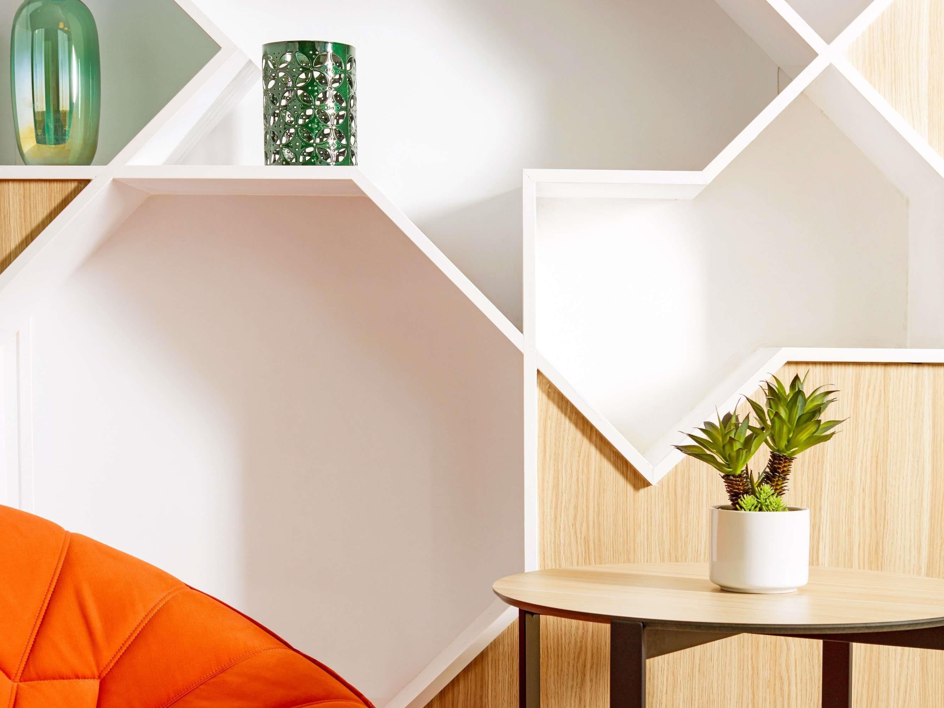 Ein modernes Interieur mit geometrischen Regalen, einem runden Tisch und einem Blumentopf.