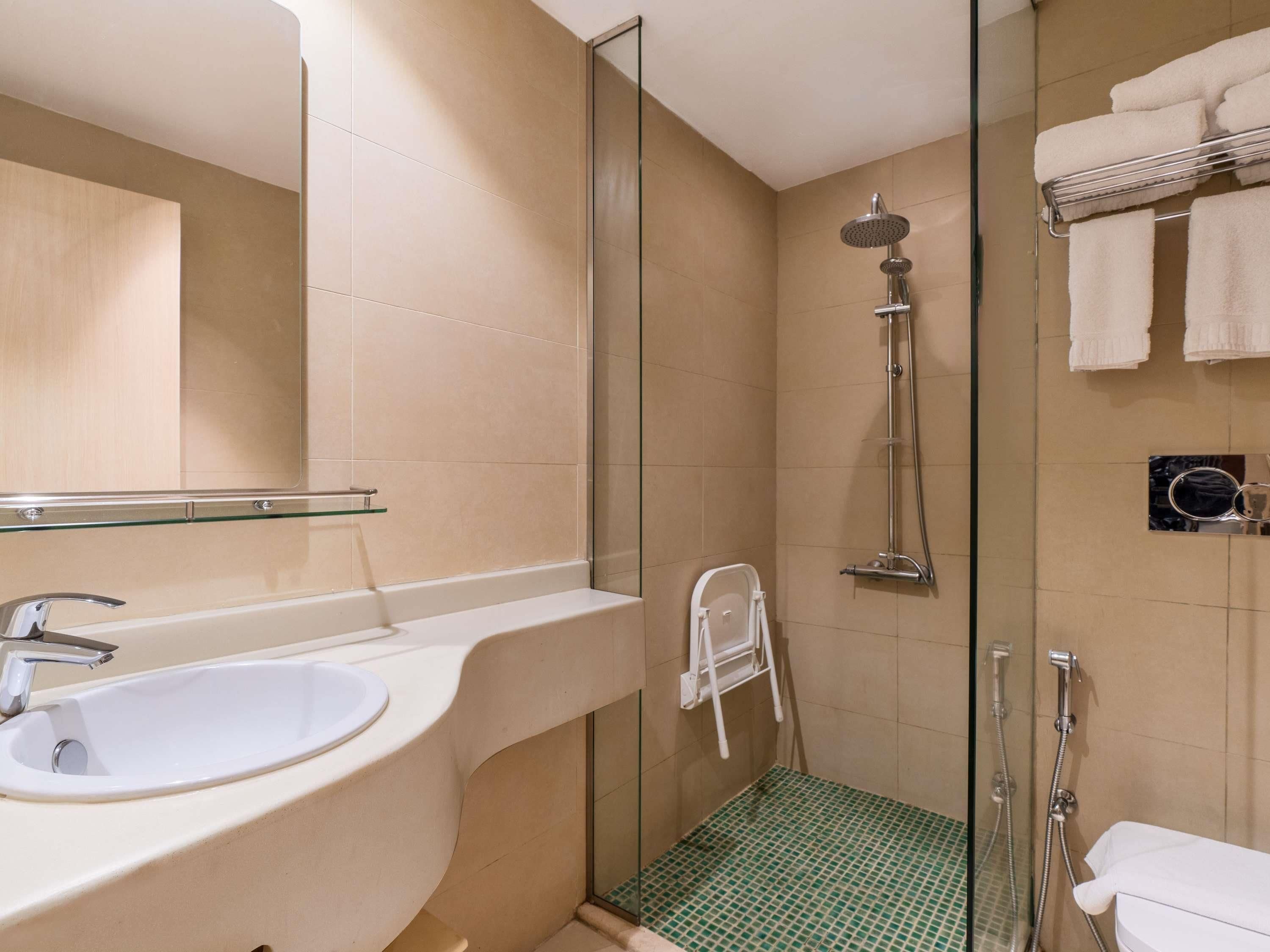 Un baño moderno con cabina de ducha de vidrio, un lavabo blanco y una repisa de cristal.