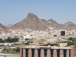 A cityscape with a prominent mountain in the background, a large building with a sign reading "King Faisal Hospital," and a mix of residential and commercial buildings. - ibis Styles Makkah (Makkah)