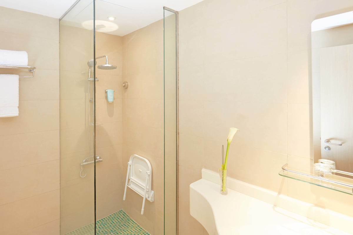 A modern bathroom with a glass-enclosed shower, a white sink, and a mirror.