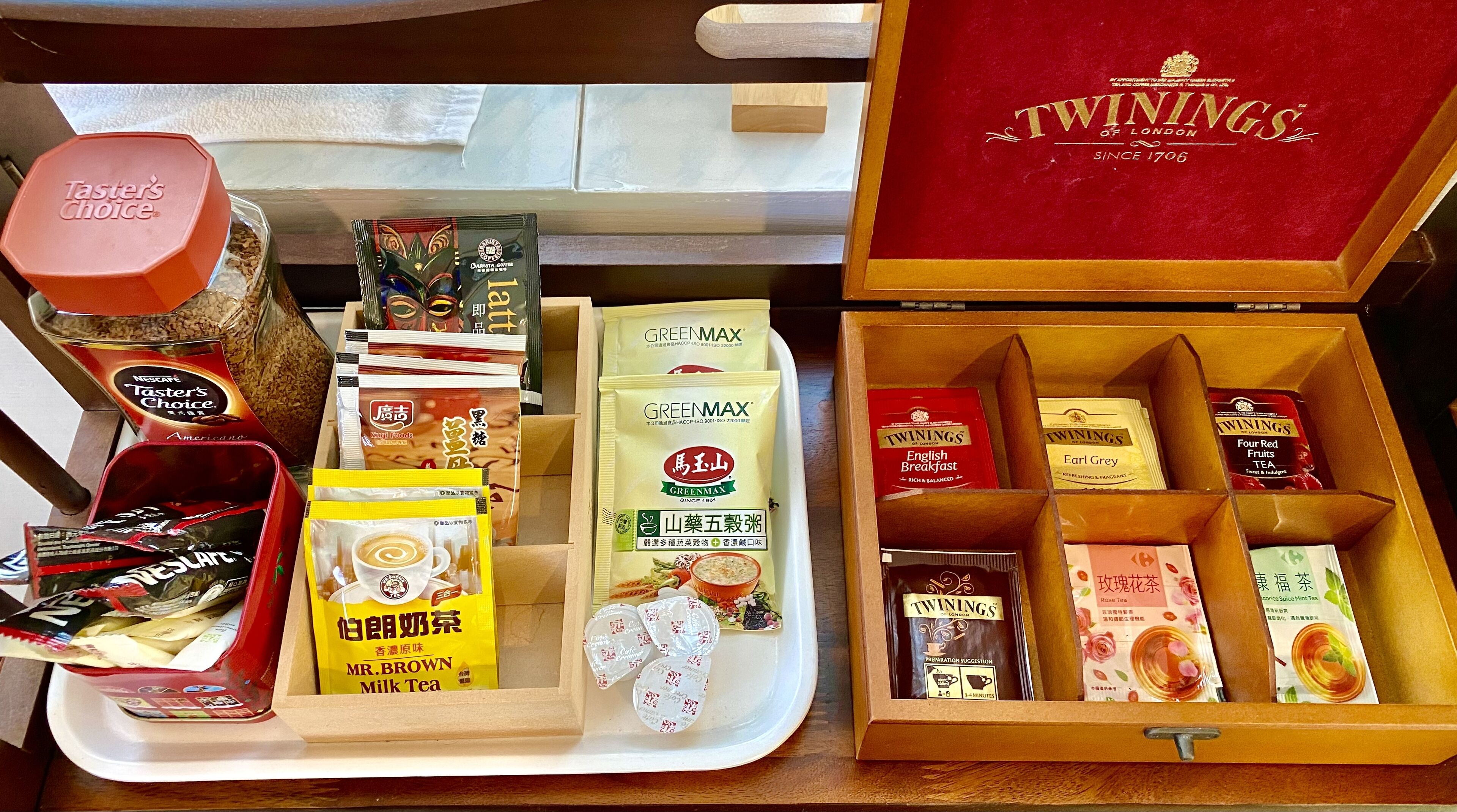 A variety of tea and coffee products, including Twinings of London, GreenMax, and Mr. Brown Milk Tea, arranged on trays and in boxes.
