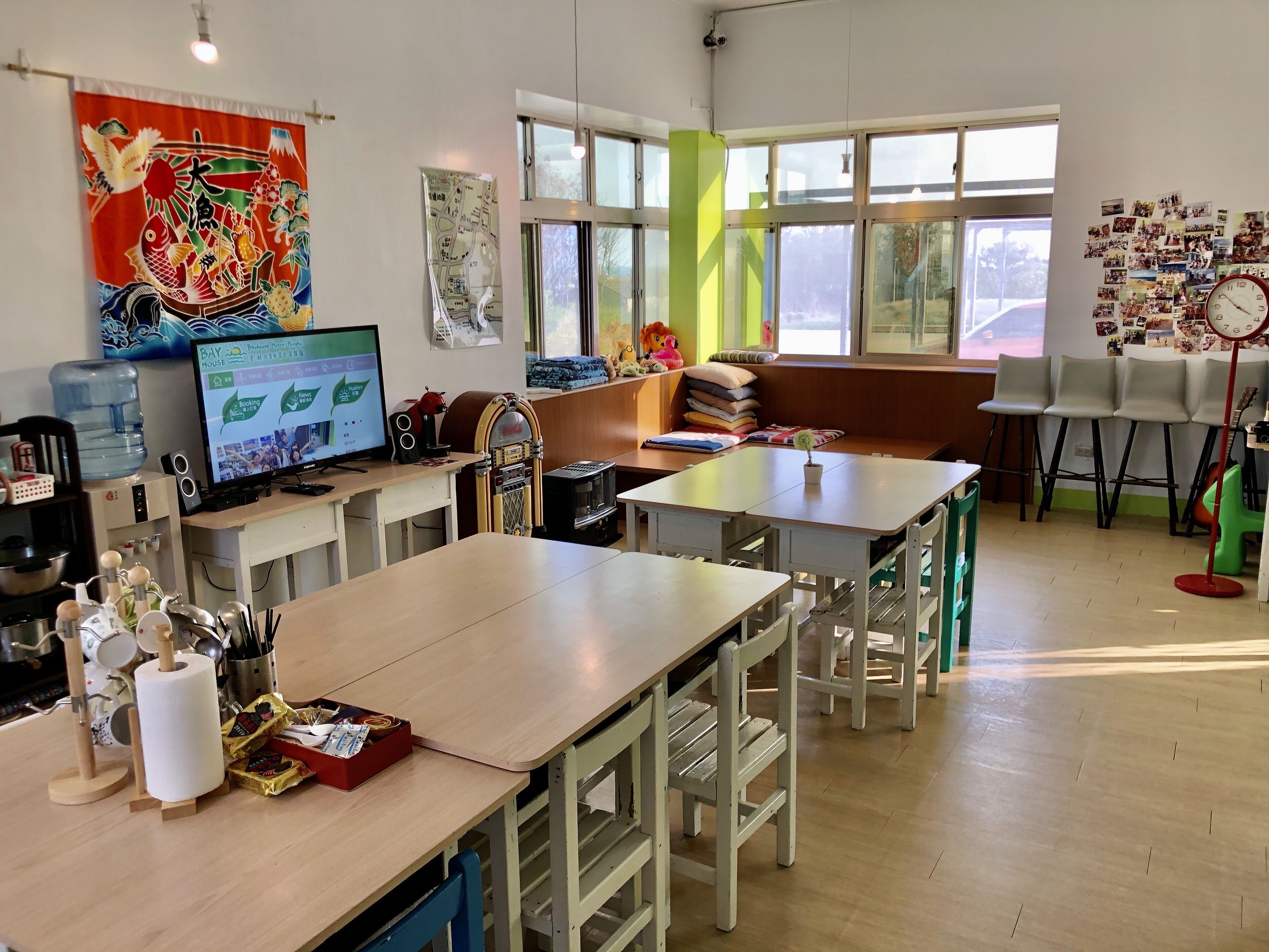A modern room with a large window, a desk with a computer, a water dispenser, and a seating area with a bench and chairs.