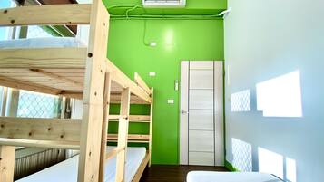 A room with bunk beds, a green wall, a white door, and a window.