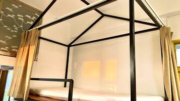 A bunk bed with a black metal frame and white bedding, curtains on both sides, and a wall with a decorative pattern.