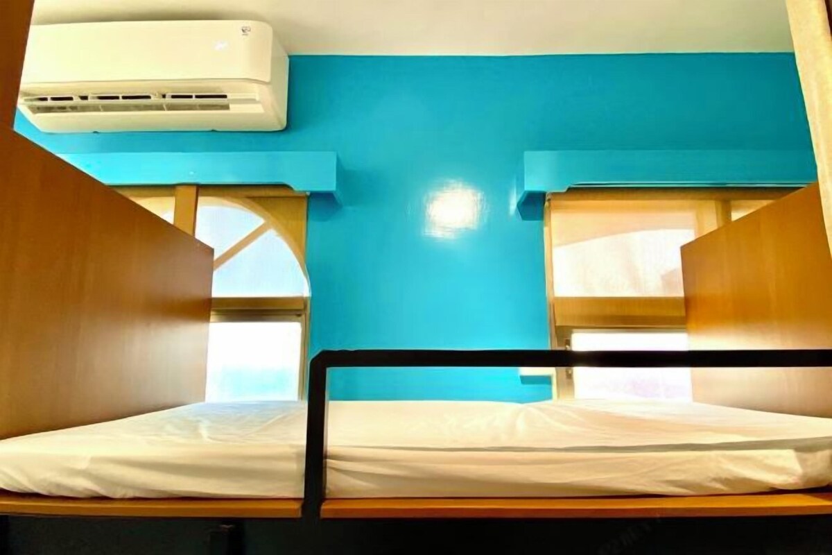A bunk bed room with a blue wall and an air conditioning unit above it.