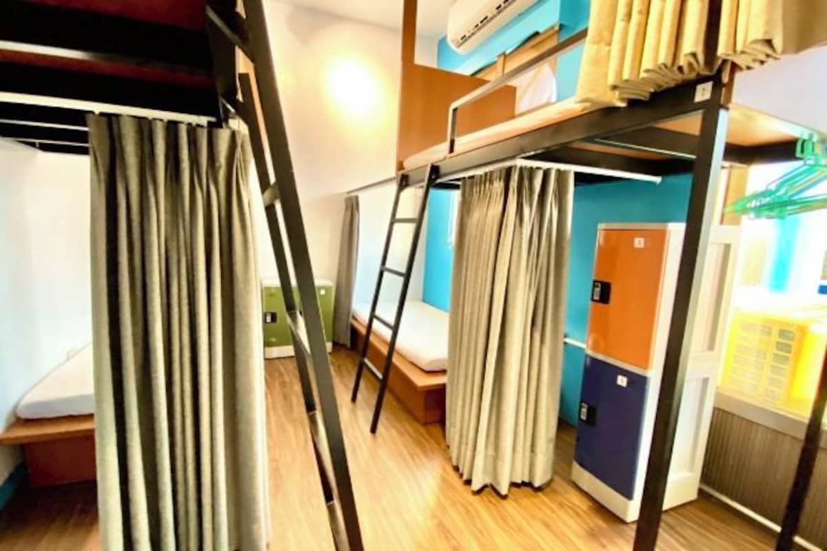 A bunk bed room with a ladder, a desk, and a wardrobe.