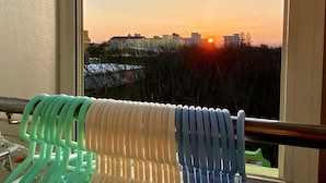 Vista desde una ventana con baranda de metal, sobre un paisaje urbano al atardecer.