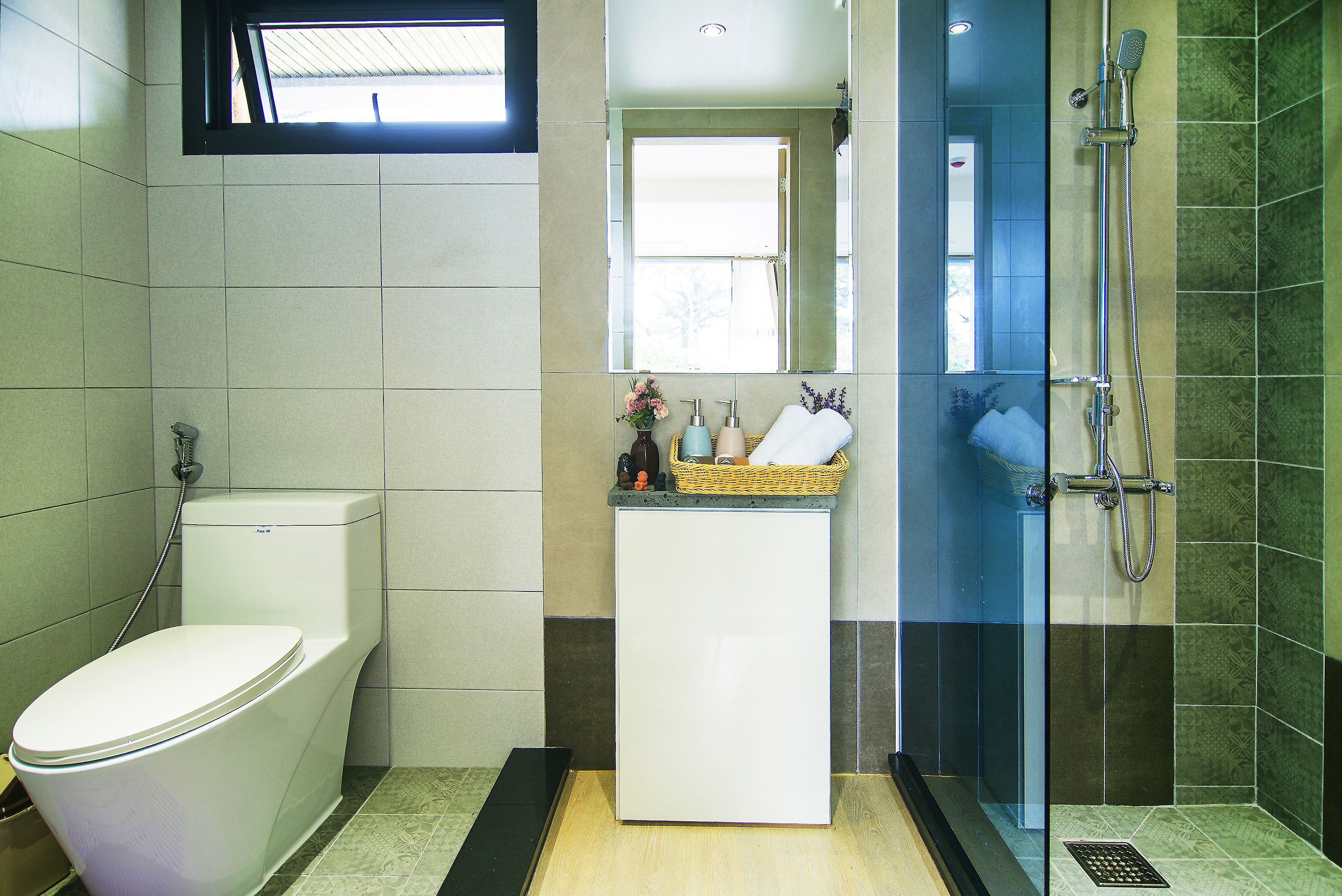 A bathroom with a toilet, a sink with a mirror, and a shower area.