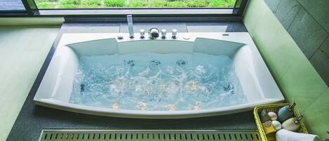 Une grande baignoire sur pieds, placée de manière à offrir une vue sur une pelouse verdoyante par la fenêtre.