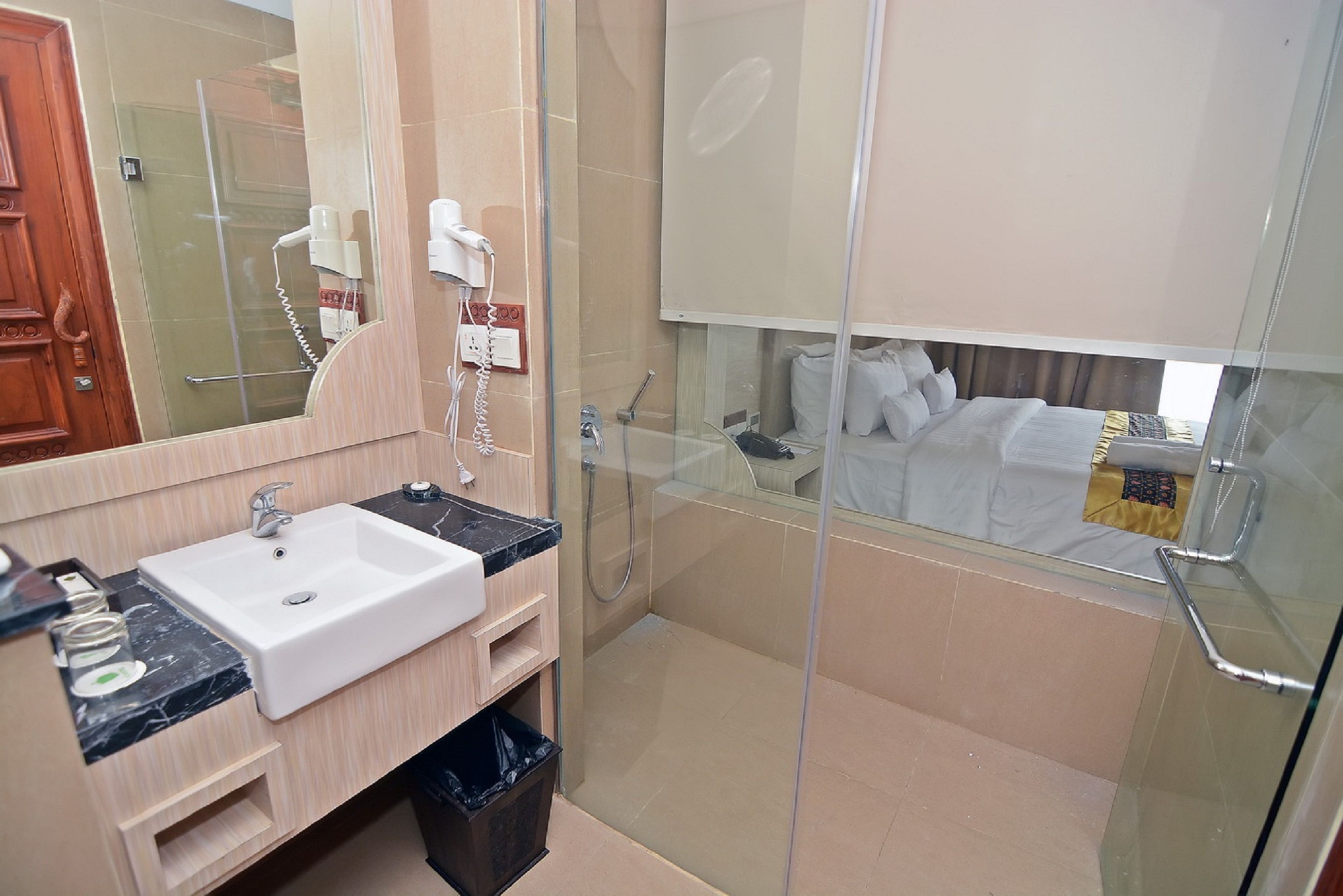 A modern bathroom with a sink, mirror, and glass shower enclosure.