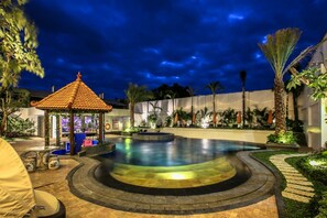 Una piscina al aire libre, sombrillas, sillones reclinables de piscina