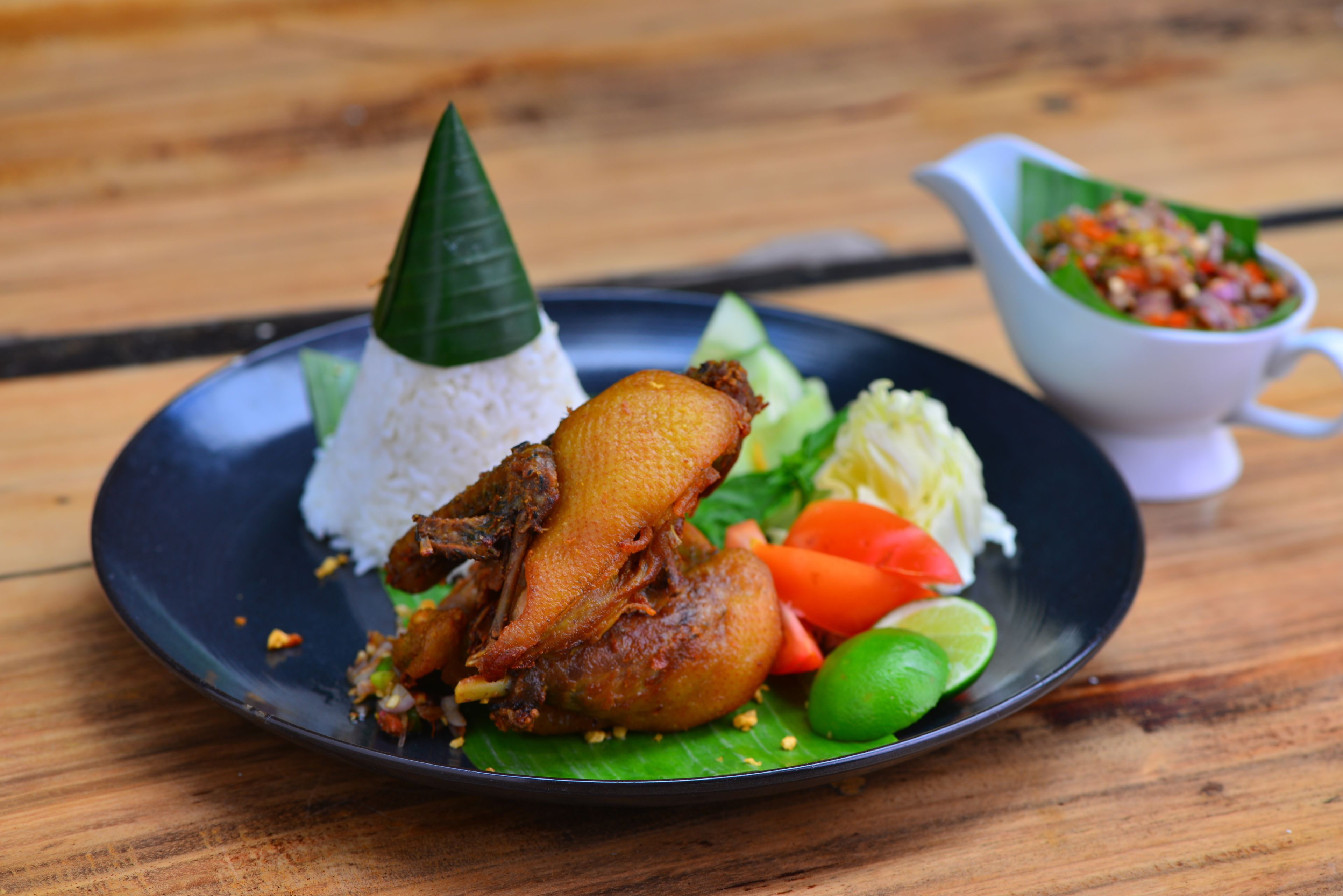 A plate of food with rice, meat, vegetables, and a small bowl of sauce.