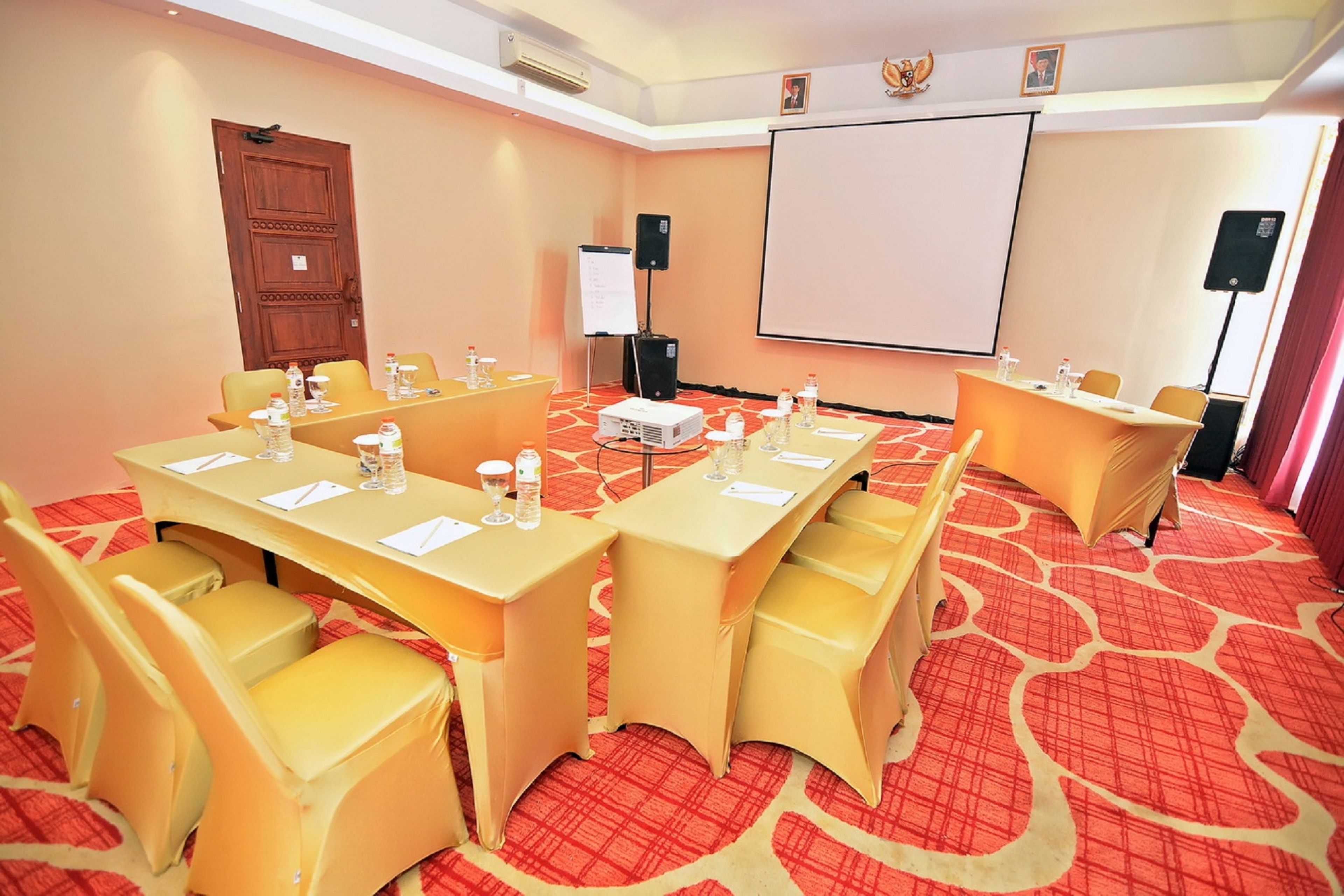 A conference room with a large table, chairs, a projector, and a screen.