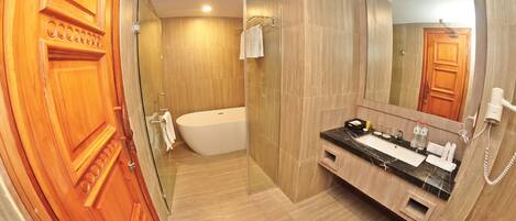 A modern bathroom with a wooden vanity, a freestanding bathtub, and a large mirror.