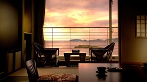 Une pièce avec vue sur la mer, une table avec des chaises et une porte coulissante de style japonais traditionnel.