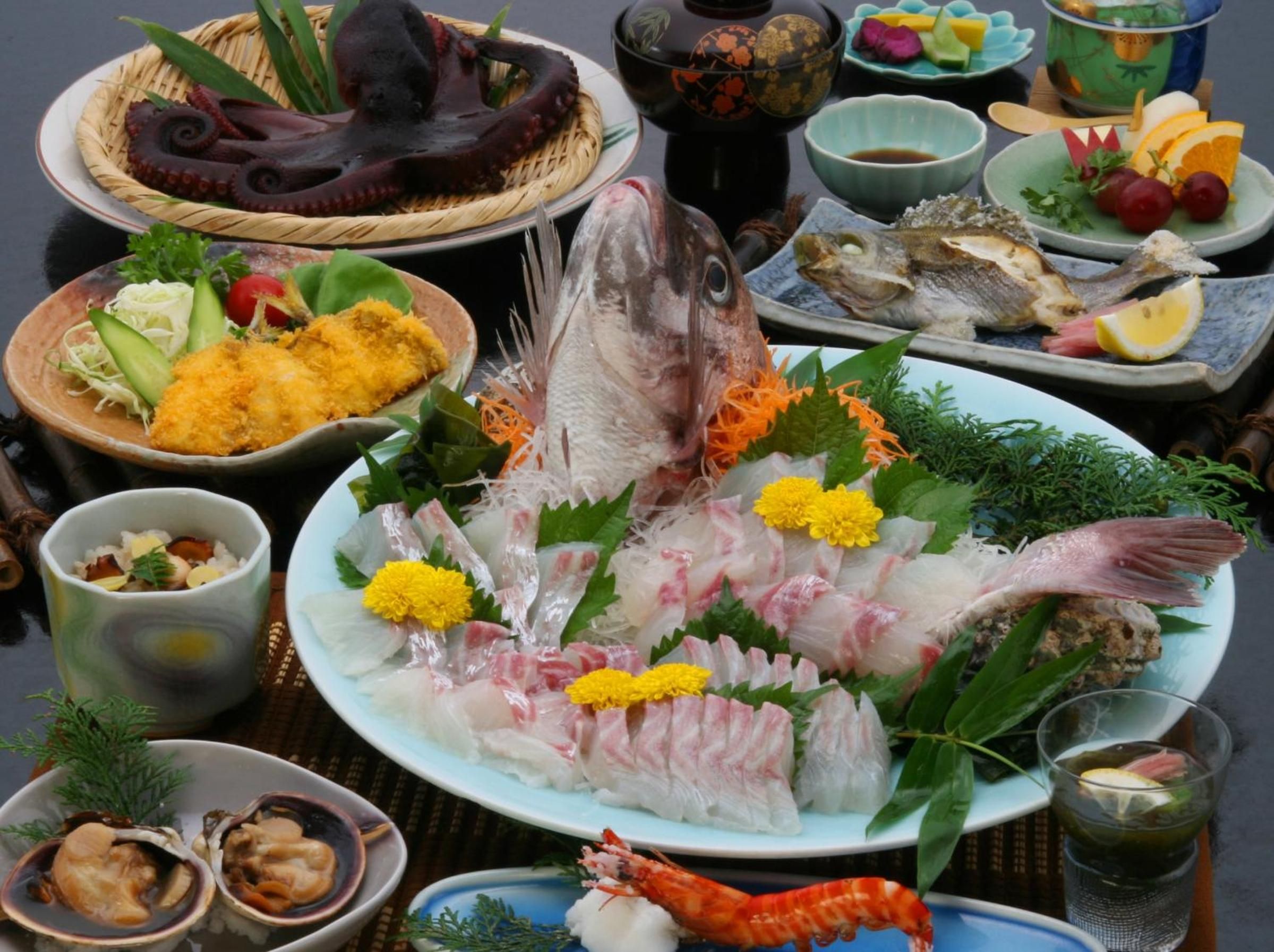 Une variété de plats de fruits de mer, notamment du poulpe, du poisson et des crevettes, présentés sur une table recouverte d’un tapis tressé.