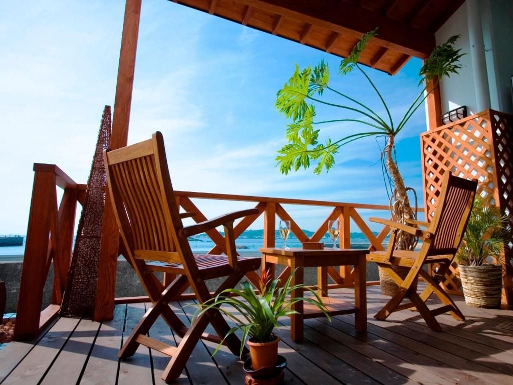 A wooden deck with chairs and a table, overlooking a body of water.
