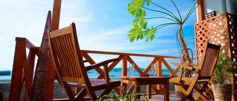 A wooden deck with chairs and a table, overlooking a body of water.