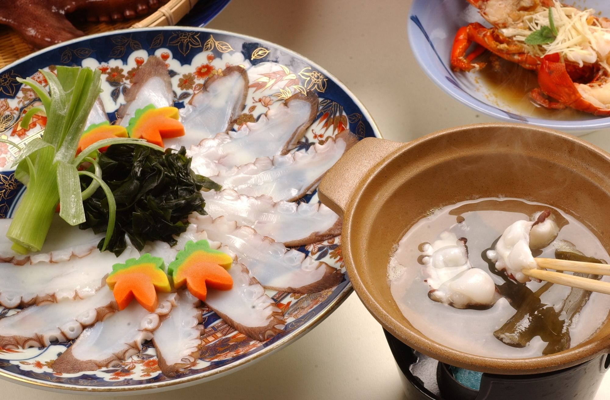 A table with a variety of dishes including seafood, vegetables, and a bowl of soup.