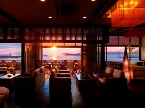 Un'accogliente area relax con posti a sedere e vista sul tramonto sull'acqua.